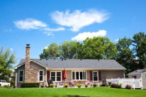 A single-story home with a brick chimney, patio set, and red umbrella—3 Mountains Home Services team caring for the yard and landscape.
